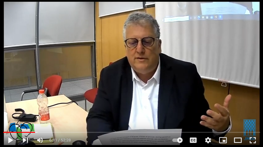 Screen shot of prof. Avriel Bar Levav's seminar. He is reading some papers that he is holding in his hand.